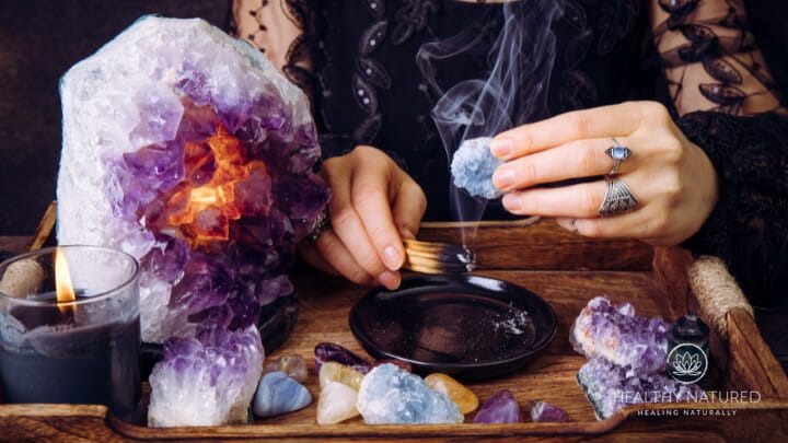 a woman holds a crystal in smudge smoke to cleanse it 