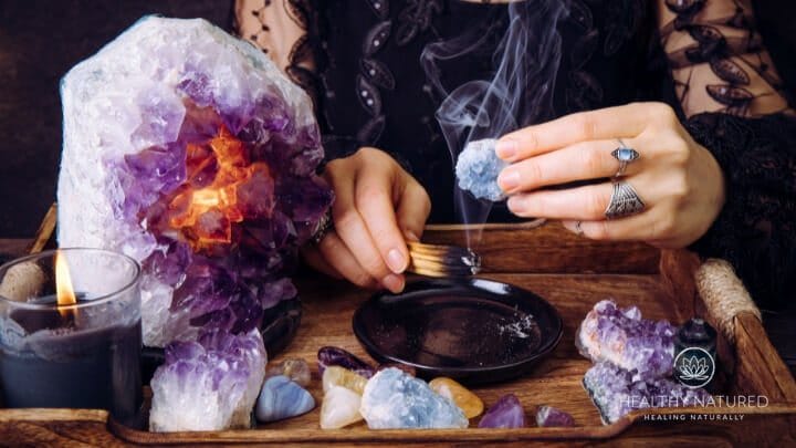 cleansing a crystal for healing with smudge a woman holds a crystal in smudge smoke to cleanse it