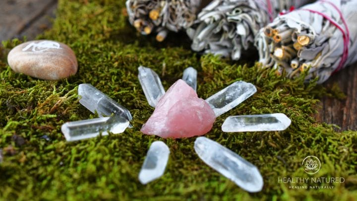 A crystal grid with clear and rose quartz, sage smudge and a reiki symbol