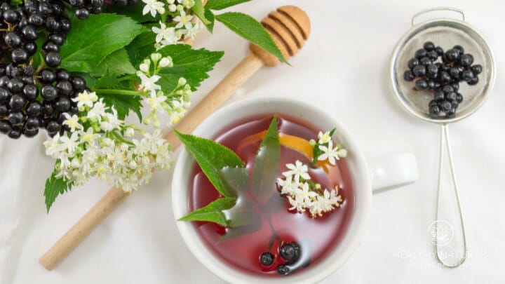 elderberries and linden flowers beside a cup of elderberry and linden tea